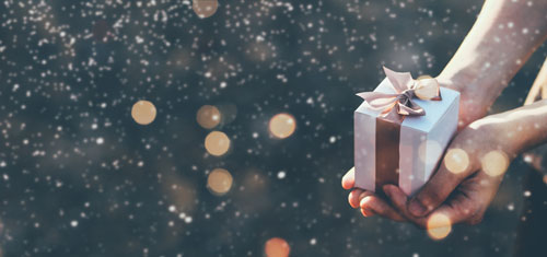 Beitragsbild zeigt ein Geschenk, das mit Schnee berieselt wird