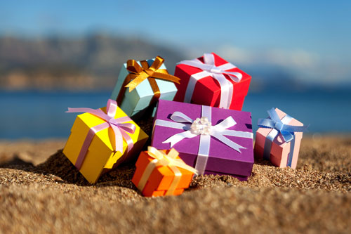 Beitragsbild zeigt einen Haufen Geschenke auf einem Sandstrand