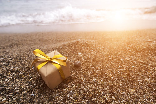 Beitragsbild für Kreditkarten-Neukundenaktionen im Juni zeigt ein Geschenk an einem Sandstrand