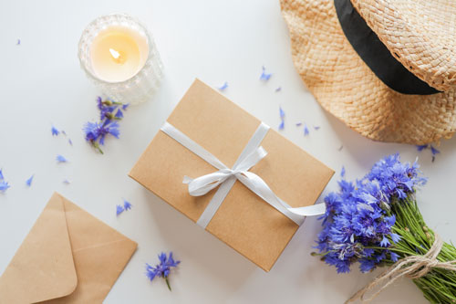 Beitragsbild für Kreditkarten-Neukundenaktionen im Juni zeigt ein Geschenk, einen Strohhut und einen Strauß Kornblumen
