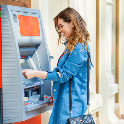 Junge Frau hebt Geld am Geldautomaten ab