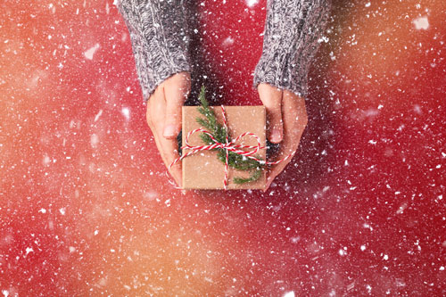 Beitragsbild für News illustriert das Thema mit einem winterlichen Geschenk verziert mit Tannenzweig, um das leicht Schnee rieselt