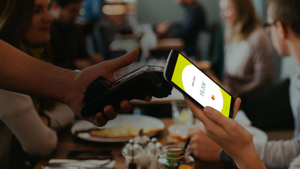 Nutzer hält Smartphone mit boon.-App an Kassenterminal