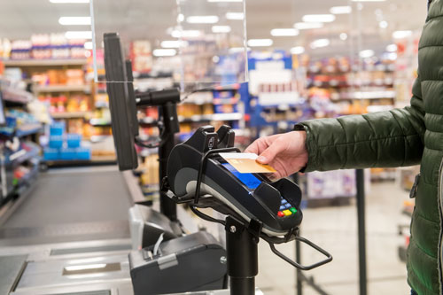 Bild zeigt kontaktloses Bezahlen mit der Karte an einer Kasse im Supermarkt